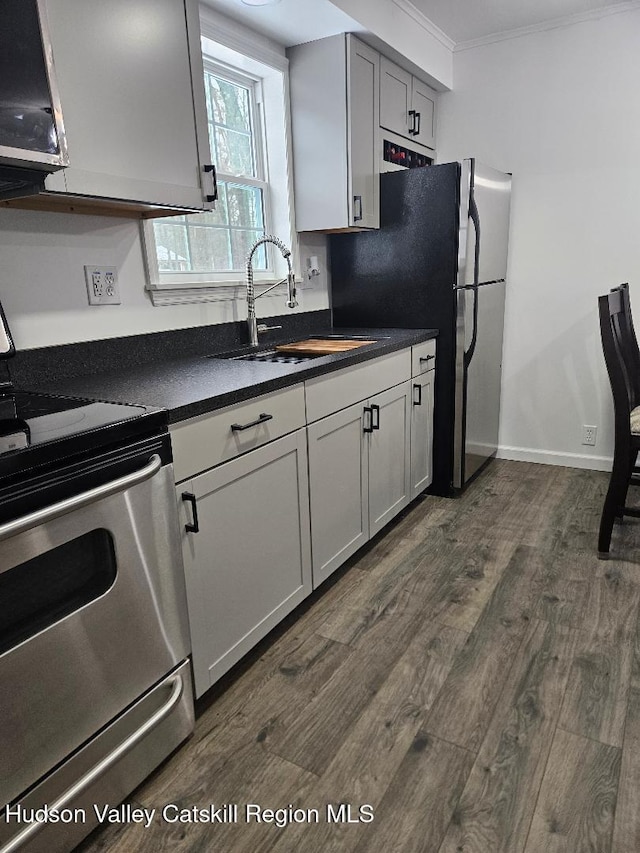 kitchen with ornamental molding, a sink, dark countertops, dark wood-style floors, and range