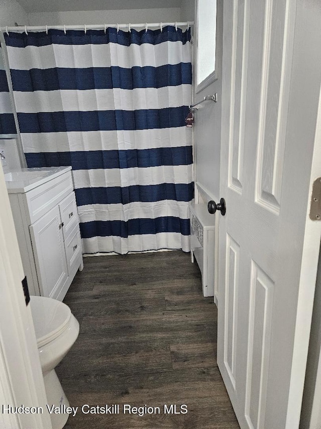 full bath with toilet, vanity, radiator heating unit, and wood finished floors