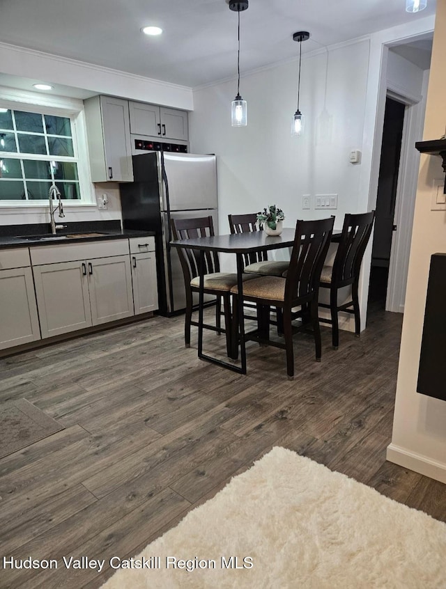 kitchen featuring dark countertops, a sink, crown molding, freestanding refrigerator, and dark wood-style flooring