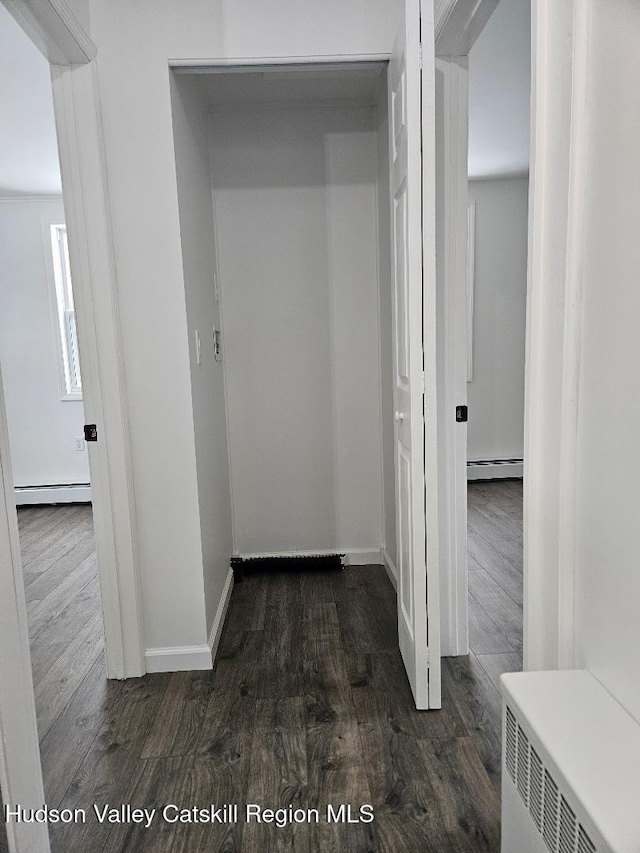 hallway with dark wood-style floors, baseboards, and a baseboard radiator