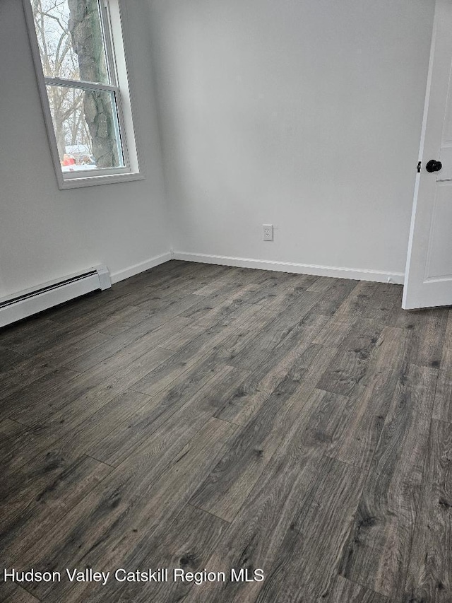 unfurnished room with dark wood-style floors, baseboard heating, and baseboards