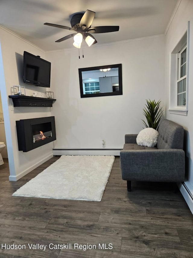 interior space featuring dark wood-type flooring, a baseboard heating unit, a glass covered fireplace, crown molding, and ceiling fan