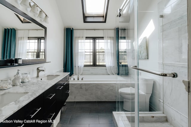 bathroom featuring a skylight, toilet, plenty of natural light, and a relaxing tiled tub