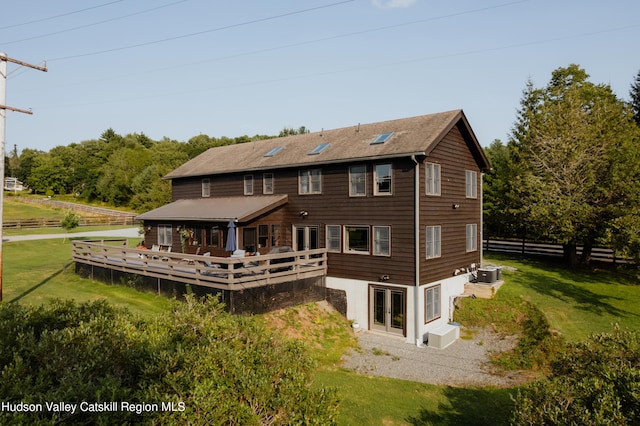 rear view of house with a lawn, central air condition unit, and a wooden deck