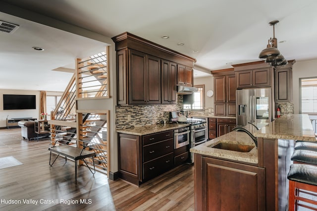 kitchen with hardwood / wood-style floors, a healthy amount of sunlight, decorative light fixtures, and appliances with stainless steel finishes