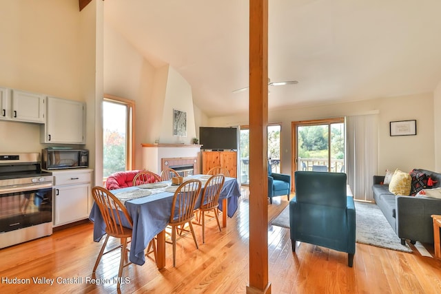 28 Loo Bridge Ln Unit 22A, Windham, NY 12496 - dining space with a tiled fireplace, light wood-style flooring, and high vaulted ceiling