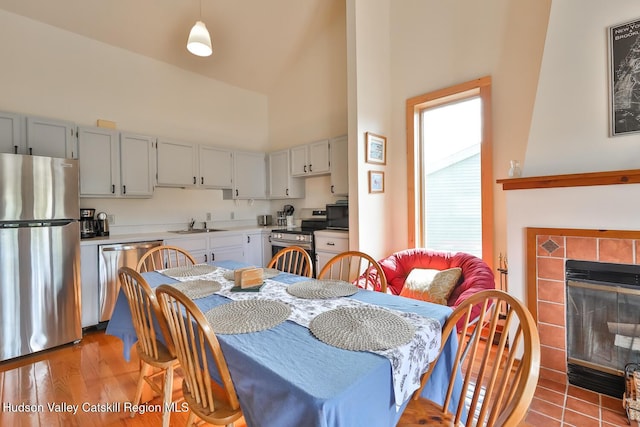 28 Loo Bridge Ln Unit 22A, Windham, NY 12496 - dining area featuring high vaulted ceiling, a tile fireplace, and light wood-style floors