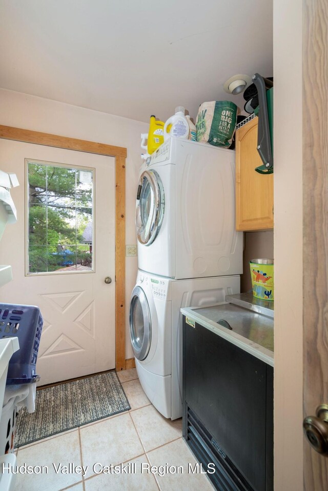 59 Mountain Dr, Hunter, NY 12442 - laundry area featuring stacked washing machine and dryer, light tile patterned flooring, and cabinet space