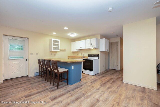 59 Mountain Dr, Hunter, NY 12442 - kitchen featuring electric range, a kitchen bar, white cabinetry, light wood-style flooring, and a peninsula
