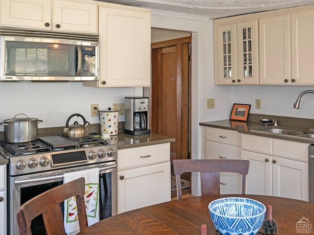 2456 State Route 82, Ancram, NY 12502 - kitchen featuring appliances with stainless steel finishes, a sink, dark countertops, glass insert cabinets, and white cabinetry