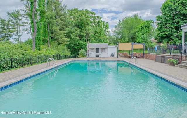 view of swimming pool featuring a patio area and an outbuilding