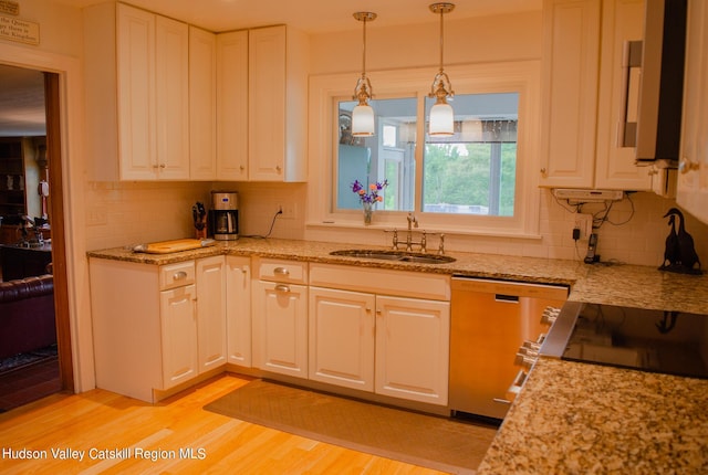 kitchen with decorative backsplash, light wood-type flooring, stainless steel dishwasher, sink, and white cabinetry