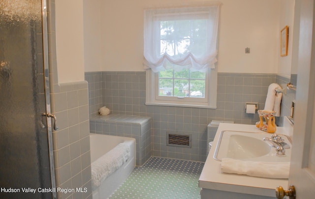 bathroom with vanity, shower with separate bathtub, and tile walls