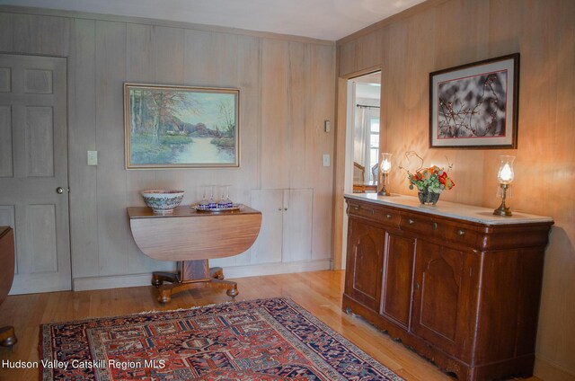 corridor with light hardwood / wood-style floors and wooden walls