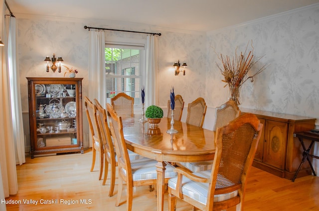 dining space featuring crown molding and light hardwood / wood-style flooring