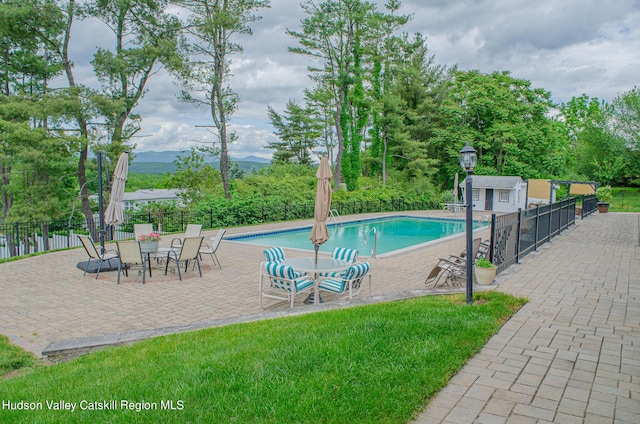 view of pool featuring a yard, an outbuilding, and a patio