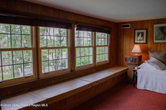 bedroom with carpet flooring and wood walls