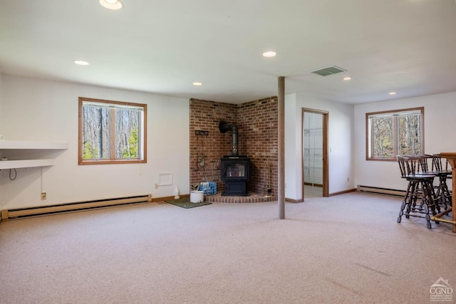 213 Botti Dr, Hunter, NY 12442 - carpeted living room featuring a baseboard radiator, healthy amount of natural light, a wood stove, and recessed lighting