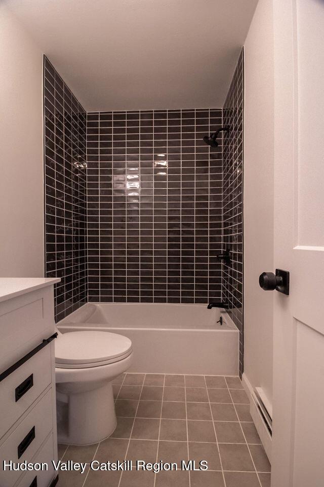11 Old Farm Rd, Napanoch, NY 12458 - bathroom with vanity, tile patterned flooring, toilet, a baseboard heating unit, and shower / bathing tub combination