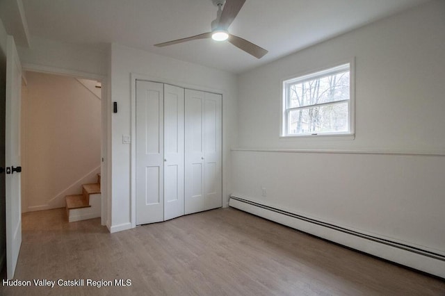 11 Old Farm Rd, Napanoch, NY 12458 - unfurnished bedroom featuring a closet, a baseboard radiator, ceiling fan, and light wood-style floors