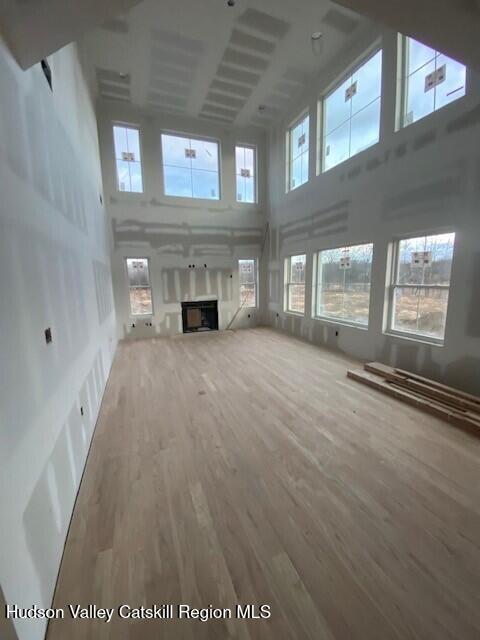 unfurnished living room featuring a towering ceiling and hardwood / wood-style flooring