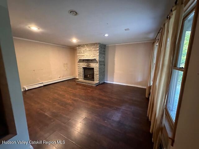 unfurnished living room featuring a stone fireplace, dark hardwood / wood-style flooring, and a baseboard radiator