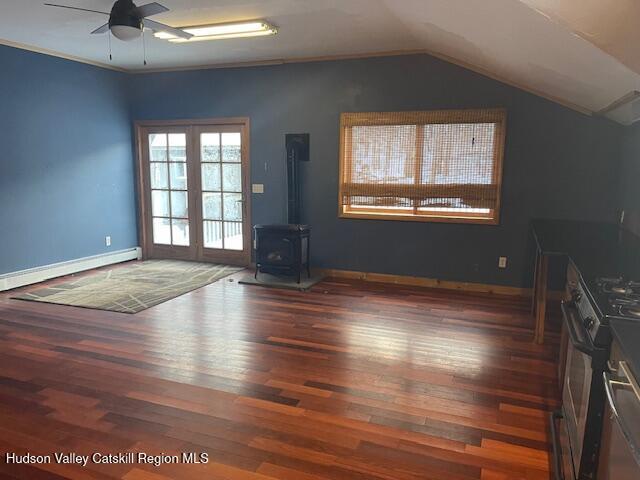 unfurnished living room with lofted ceiling, a wood stove, ceiling fan, baseboard heating, and dark hardwood / wood-style flooring