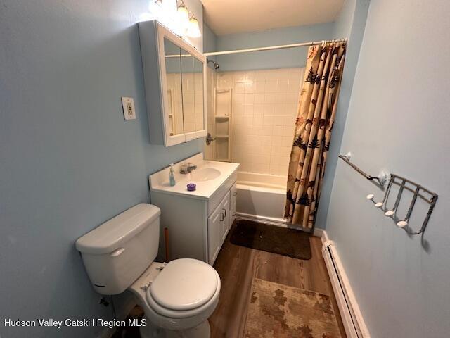 full bathroom with vanity, wood-type flooring, a baseboard radiator, shower / bathtub combination with curtain, and toilet