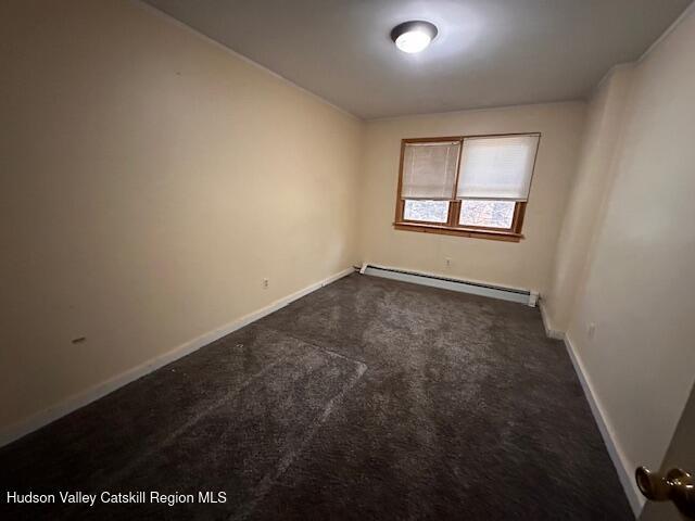 unfurnished room featuring dark colored carpet and baseboard heating