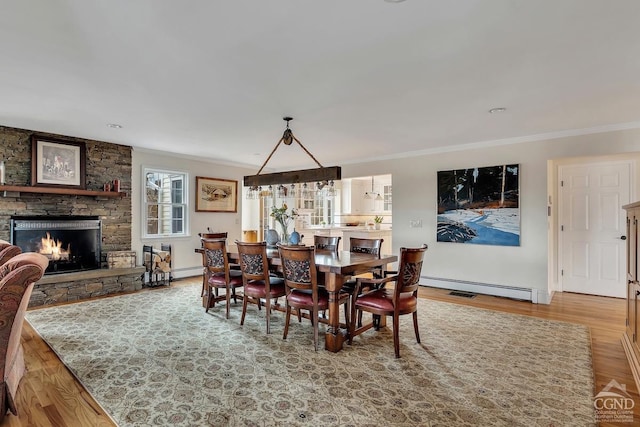 311 County Route 13, Old Chatham, NY 12136 - dining room with crown molding, a baseboard heating unit, wood finished floors, a stone fireplace, and baseboards
