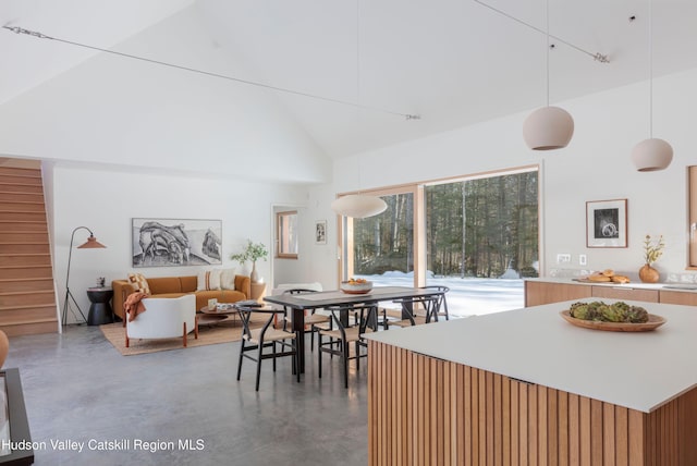 dining space with high vaulted ceiling and concrete floors