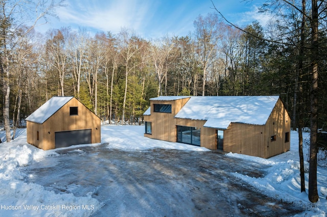 exterior space with a garage, an outdoor structure, and a view of trees