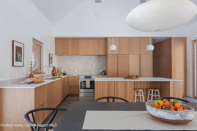 kitchen featuring a sink, stainless steel range with electric cooktop, light countertops, modern cabinets, and pendant lighting