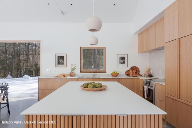 kitchen featuring stainless steel electric range oven, light countertops, decorative light fixtures, and a center island