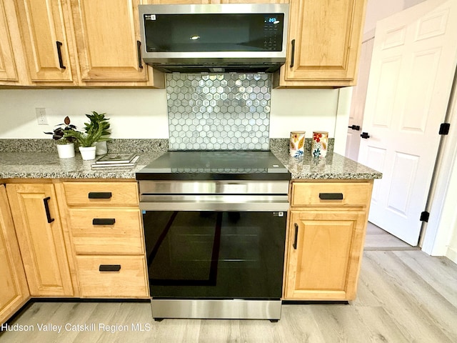 kitchen featuring decorative backsplash, light wood-type flooring, stainless steel appliances, and dark stone counters