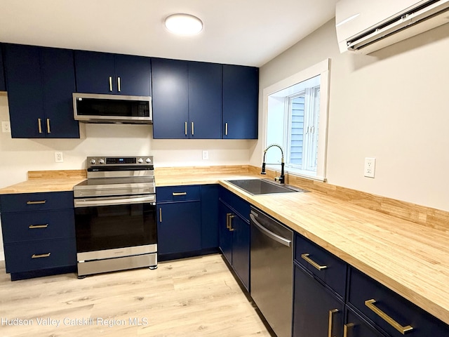 kitchen featuring wood counters, sink, blue cabinetry, stainless steel appliances, and a wall unit AC