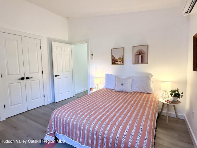 bedroom with a wall mounted air conditioner, hardwood / wood-style floors, and a closet