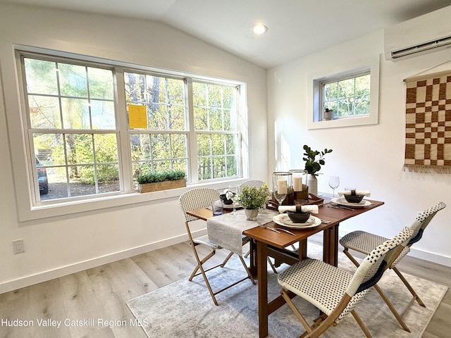 dining space with wood-type flooring, an AC wall unit, and a healthy amount of sunlight