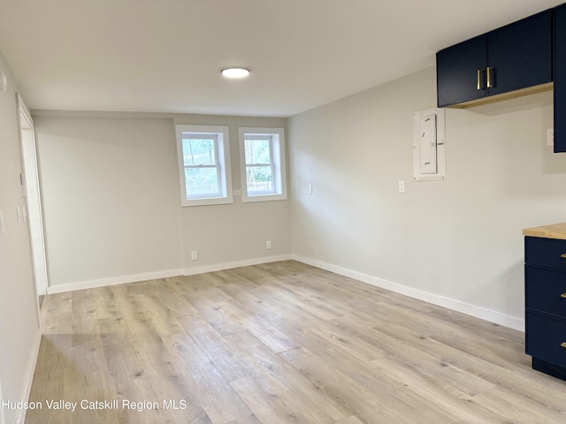 empty room with electric panel and light hardwood / wood-style flooring