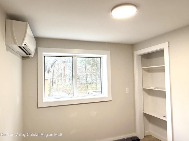 unfurnished bedroom with a wall unit AC and a closet