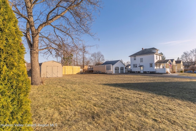 view of yard featuring a storage unit, an outbuilding, a garage, and fence