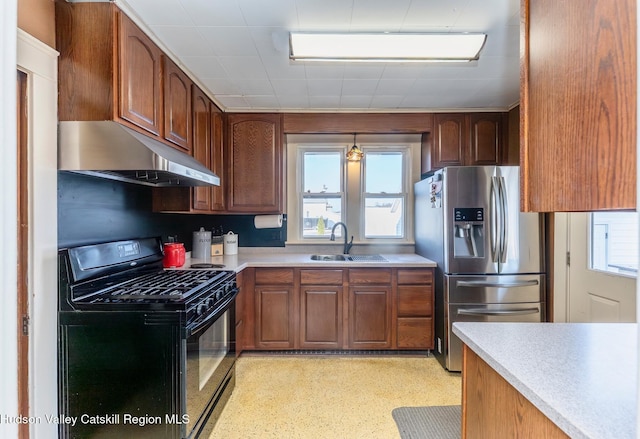 kitchen featuring a healthy amount of sunlight, a sink, black gas range, under cabinet range hood, and stainless steel fridge