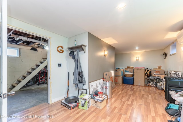 basement featuring stairway, concrete block wall, and light wood finished floors