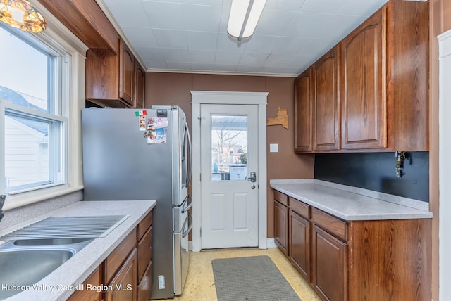 kitchen featuring a sink, brown cabinets, stainless steel refrigerator with ice dispenser, and light countertops