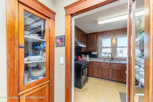 kitchen featuring black gas stove, a sink, light countertops, under cabinet range hood, and brown cabinets