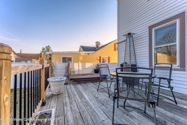 wooden terrace with outdoor dining area and an outdoor hot tub