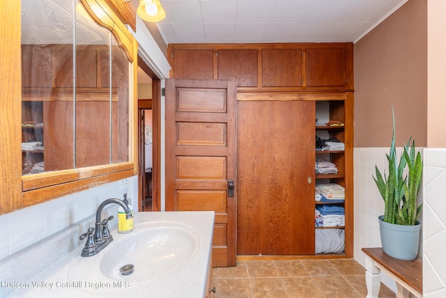 bathroom with tile patterned flooring, wainscoting, tile walls, and vanity