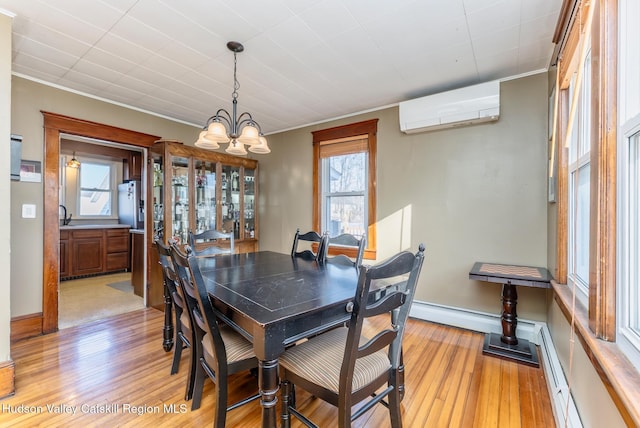 dining room featuring light wood-style floors, an AC wall unit, a chandelier, and a healthy amount of sunlight