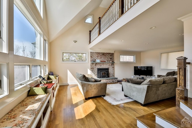 88 Gaby Ln, Hunter, NY 12442 - living room featuring a towering ceiling, healthy amount of natural light, a brick fireplace, wood finished floors, and baseboards