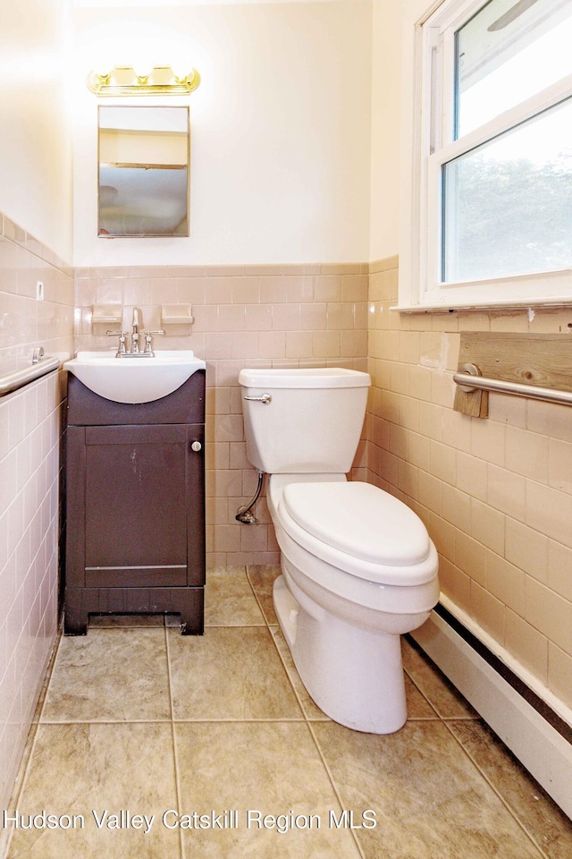 55 Harry Wells Rd, Saugerties, NY 12477 - bathroom featuring tile walls, baseboard heating, toilet, a wainscoted wall, and vanity